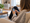A female teen sitting on a couch at home in a cozy family room using a smartphone.
